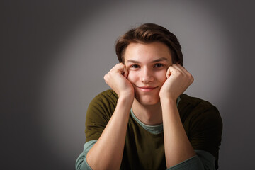 Fashion glamorous portrait of a handsome boy in on dark background in studio.