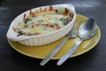 Baked spinach lasagna with cheese in white bowl on yellow plate