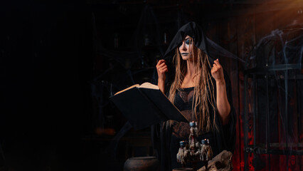 Halloween concept. Witch dressed black hood with dreadlocks standing dark dungeon room use magic...