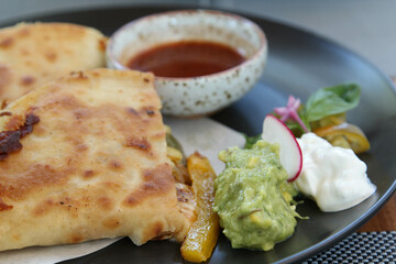 Italian pizza calzone with vegetable, salad and sauce on black plate