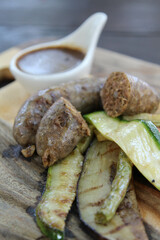 Sausage and fried vegetable served with sauce on wooden plate