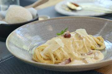 Spaghetti carbonara with fried pork in grey ceramic bowl