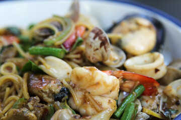 Stir fried spaghetti seafood on white ceramic plate