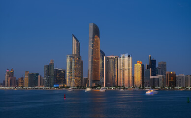 Blue hour cityscape with the skyline of Abu Dhabi. Travel to United Arab Emirates, view to modern skyscraper office buildings.