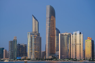 Fototapeta na wymiar Blue hour cityscape with the skyline of Abu Dhabi. Travel to United Arab Emirates, view to modern skyscraper office buildings.