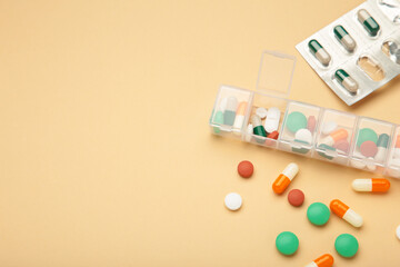 Daily pill box with medications and nutritional supplements on beige background. Space for text