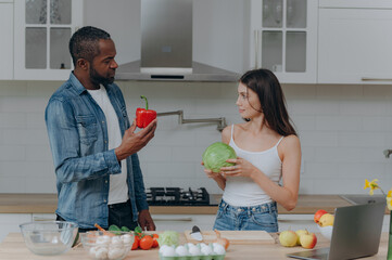 A happy interracial couple preparing food in the kitchen. an African-American man and a Caucasian...