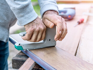 Close-up of an old man's hands fixing wooden planks. Selective focus.