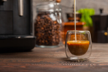 Black coffee in a glass and cream. Pour cream or milk into espresso. Coffee drink on black table background.Barista. Coffee house concept. Place for text.