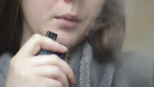 Young woman smoke vape. Female inhales vapor of electronic cigarette. Mouth close up view