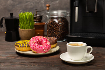 Fragrant delicious espresso coffee with pink strawberry donut, coffee machine on brown texture table. Good morning concept. Morning coffee. Sweet table. Colorful berry buns.Top view.