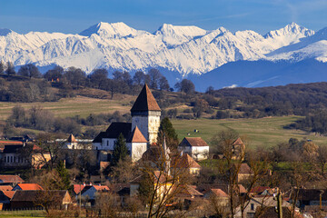 Photography of the fortified church located at Hosman, Sibiu county, Romania shot in the mid day with the Fagaras  mountains in the background.