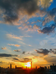 Fototapeta premium Vertical image, Twilight sunset of City skyline, two tone colors, dawn, orange and blue sky, dark clouds, buildings silhouette in the background