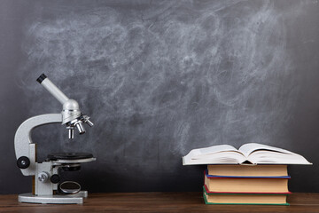 Back to school - books and microscope on the desk, Education concept. Blackboard background