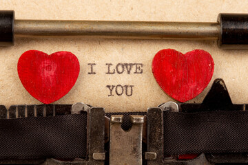I love you - phrase on typewriter. Valentines Day greetings concept. Little red wooden heart close up. Valentines greeting card.