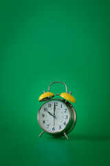 Retro silver alarm clock. 10:00.  am,  pm. Green background.