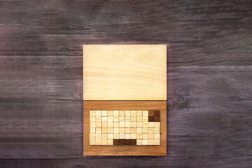 木で作ったノートパソコンを開いた正面が中央にある暗い木目の机の背景