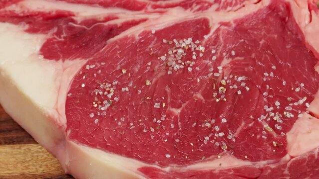 sel et &eacute;pices vers&eacute;s sur un c&ocirc;te de boeuf cru