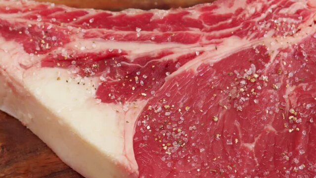 sel et &eacute;pices vers&eacute;s sur un c&ocirc;te de boeuf cru