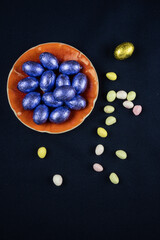 des œufs en chocolat bleu sur une coupelle orange et des petits œufs colorés autour