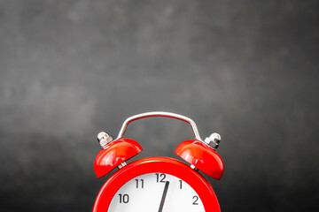 Red bell alarm clock on a dark black background with natural light. Mention of personal care...
