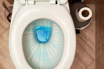 Top view of cleaning toilet with blue detergent and toilet paper. Housekeeping theme backgrounds