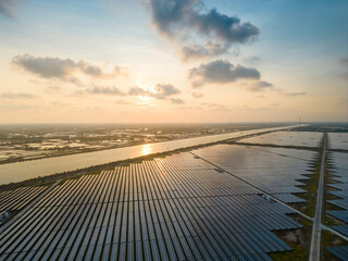 Fototapeta na wymiar Aerial view of large sustainable electrical power plant with many rows of solar photovoltaic panels for producing clean ecological electric energy in countryside with sunset sky