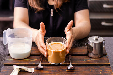 Waiter in black apron stretches a cup of coffee