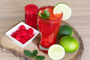 Cherry lemonade in crystal glass on brown wooden log