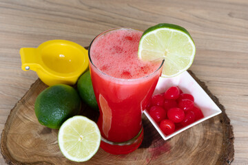 Cherry lemonade in crystal glass on brown wooden log