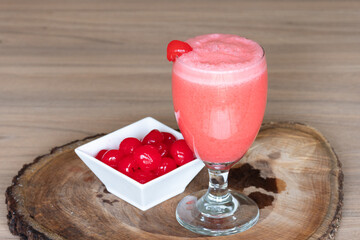 cherry milkshake in glass cup on brown wooden log