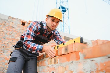 Construction worker man in work clothes and a construction helmet. Portrait of positive male builder in hardhat working at construction site.