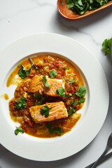 Indian-Inspired Salmon: A Vibrant Red Curry with Juicy Tomatoes, and Fried Vegetables with Fresh Cilantro on the Side. Vertical photo 