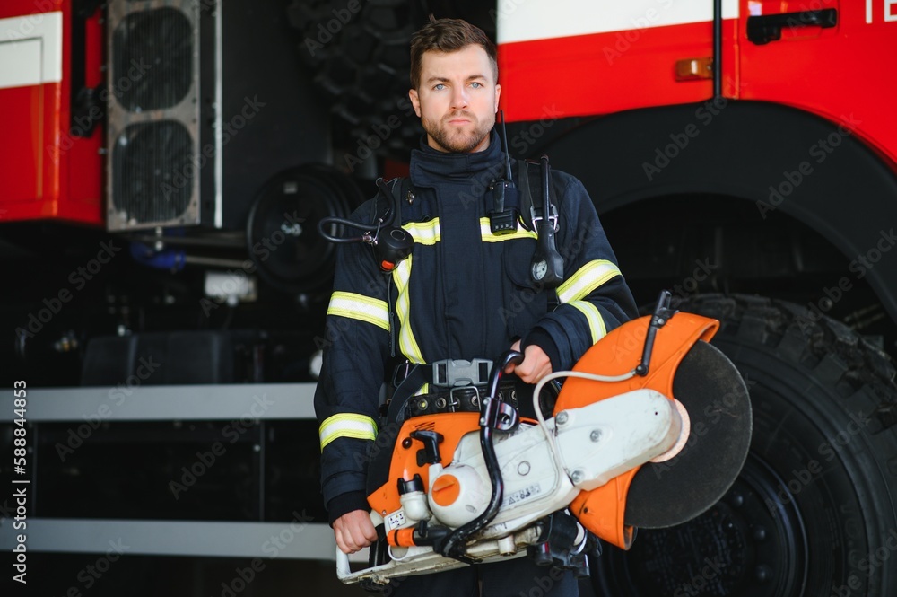 Wall mural Firefighter portrait on duty. Photo fireman with gas mask and helmet near fire engine.