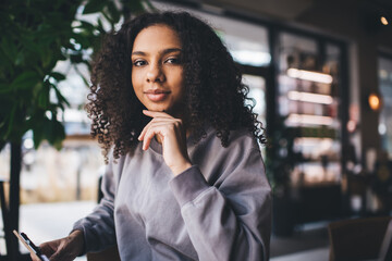 Happy black woman with smartphone in cafe