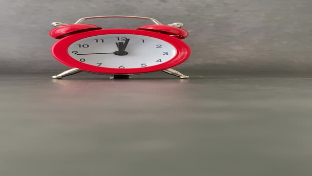 Red bell alarm clock on a dark black background with natural light. Mention of personal care schedule, reminder of medicines and physical exercise for rheumatism, arthrosis and labyrinthitis.