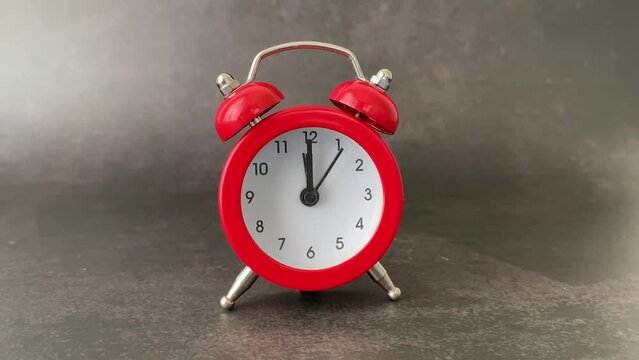 Red bell alarm clock on a dark black background with natural light. Mention of personal care schedule, reminder of medicines and physical exercise for rheumatism, arthrosis and labyrinthitis.