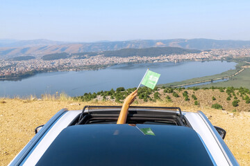 Woman holding Saudi Arabia flag from the open car sunroof,  window driving along the serpentine...