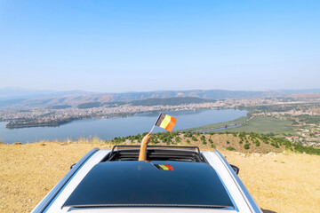 Woman holding Belgium flag from the open car sunroof,  window driving along the serpentine road in...