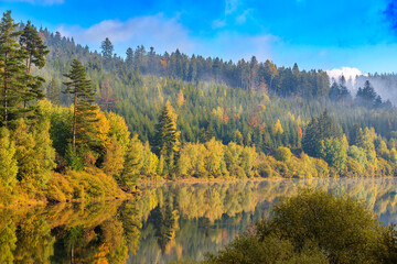Fototapeta na wymiar Lake with reflection at a Morning in autumn with a fisher who catch fishes in Black Forest, Germany