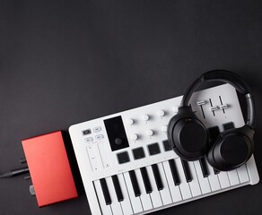 White midi keyboard, black headphones and read audio interface