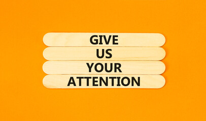 Give us your attention symbol. Concept words Give us your attention on wooden stick. Beautiful orange table orange background. Motivational business give us your attention concept. Copy space.