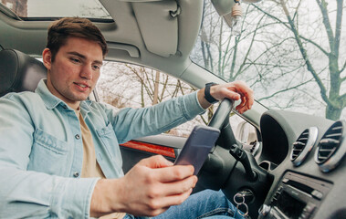 Obraz premium Young man using smartphone in car, Wroclaw, Poland
