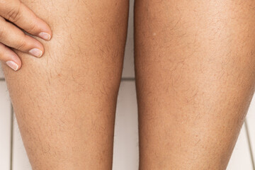 Cropped unshaven hairy woman legs with hand showing hair on skin. Everybody is normal. Body positive and feminism. Sensitive body and skin care. No more razors and depilations. Hormone health problems