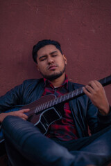 Retrato de hombre moreno relajado mientras toca su guitarra acústica clásica