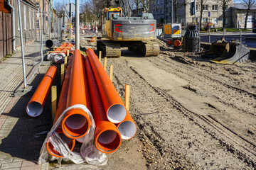 New brown plastic sewage pipes stacked on the side of the city street during reconstruction works