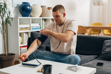 A Caucasian man is checking his blood pressure at home