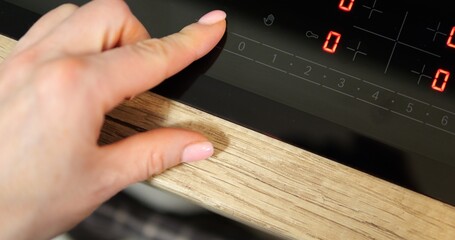 Top view woman forefinger press button turn on black induction cooktop. Close up shot of female...