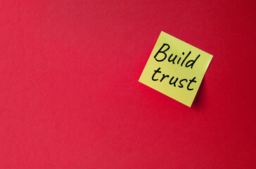 Build trust symbol. Orange steaky note with words Build trust. Beautiful red background. Business and Build trust concept. Copy space.