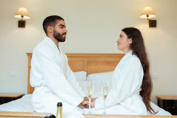 Loving Couple Holding Hands Drinking Sparkling Wine In Hotel Suite